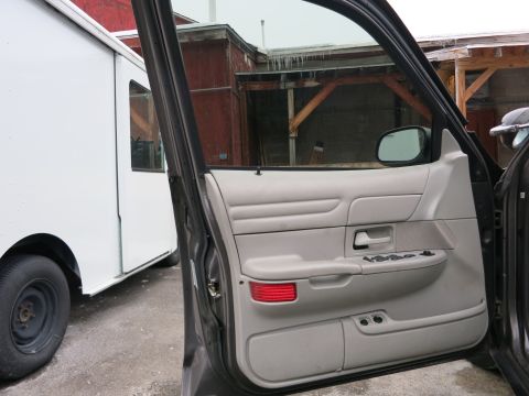 2001 Ford Crown Victoria - The interior door panel of a 2001 Ford Crown Victoria is visible, showing the armrest and window controls.