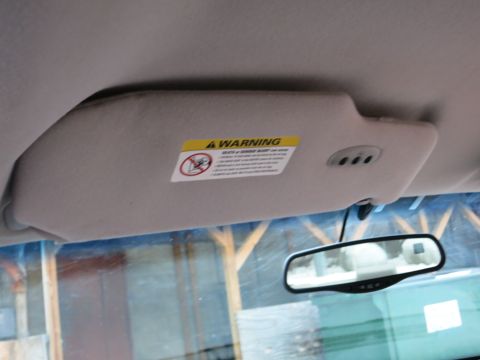 2001 Ford Crown Victoria - The interior of a vehicle, showing the sun visor with a warning label and the rearview mirror.
