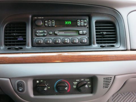 2001 Ford Crown Victoria - The dashboard features wood trim, a digital clock, and climate control knobs.