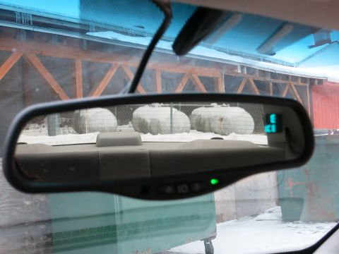 2001 Ford Crown Victoria - The rearview mirror shows a snowy scene with large tanks outside a wooden structure.