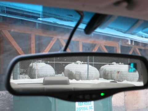 2001 Ford Crown Victoria - View through a car's interior mirror shows large, snow-covered tanks in the distance.