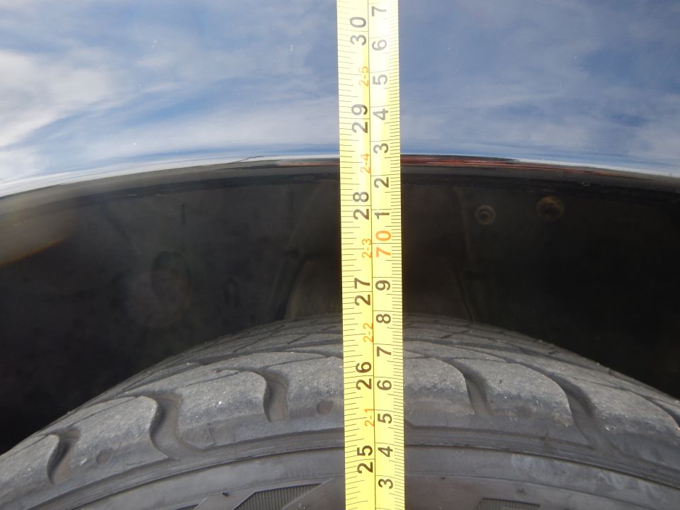 Yellow tape measure over a tire and dark fender showing about 30 inches