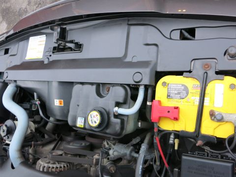 2001 Ford Crown Victoria - Close-up view of a vehicle's engine bay, highlighting the battery and coolant reservoir.