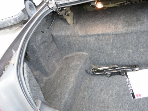 2001 Ford Crown Victoria - The interior of a car trunk, grey carpeting and a scissor jack.