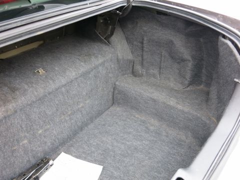 2001 Ford Crown Victoria - The interior of a car trunk is visible, lined with gray carpet and a jack tool on the floor.