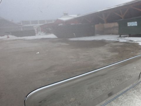 2001 Ford Crown Victoria - Reflection of buildings and dumpsters on the side of a car door.
