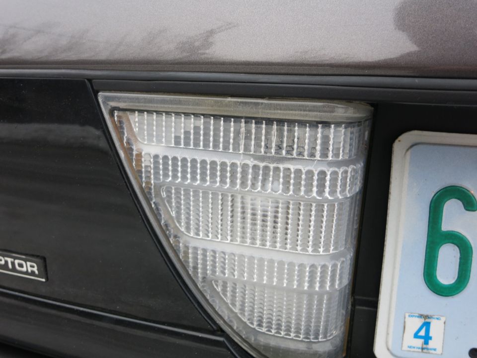 Close-up of a car's rear tail light and a license plate with the number 6