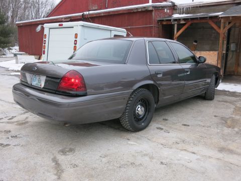 2001 Ford Crown Victoria - The rear of a dark gray 2001 Ford Crown Victoria is visible in a snowy outdoor setting.