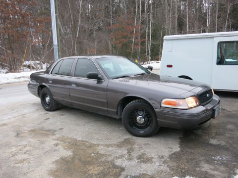 2001 Ford Crown Victoria - A 2001 Ford Crown Victoria is parked on a lot with a white van behind it.