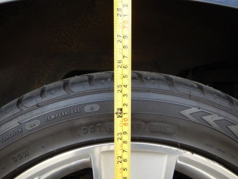 2003 Ford Crown Victoria - tape measure runs down a tire showing 98W and temperature/DOT sidewall markings, with a silver wheel visible below.