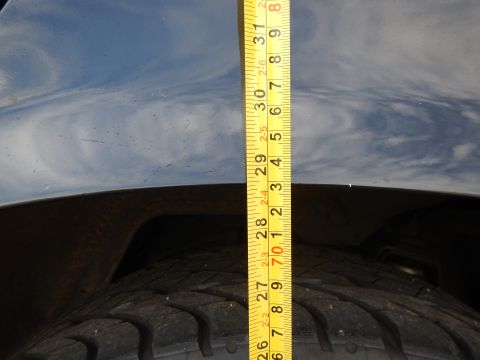 2003 Ford Crown Victoria - Vertical tape measure from a dark glossy fender lip down to the tire tread, sky reflected in the paint.