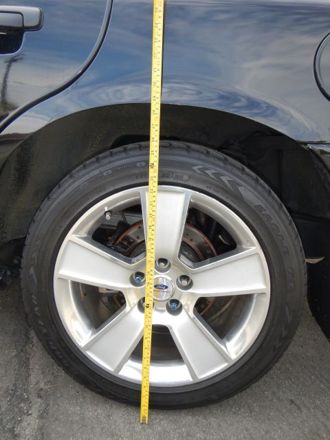 2003 Ford Crown Victoria - Silver five-spoke alloy wheel with a Ford center cap on a black car, a tape measure dropping from the fender to the ground.