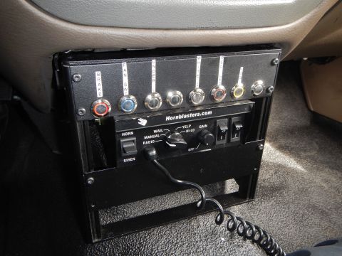 2003 Ford Crown Victoria - black Hornblasters.com control box with labeled toggle switches and a horn/siren selector mounted under a tan vehicle dashboard.