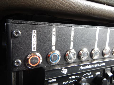 2003 Ford Crown Victoria - Angled close-up of a Hornblasters.com switch panel with red and blue illuminated toggles labeled brake and fan switch.