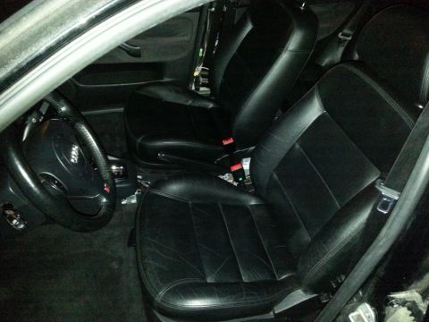 2002 Volkswagen Jetta - The interior of a car features black leather seats and a steering wheel, with exposed wiring near the dashboard.