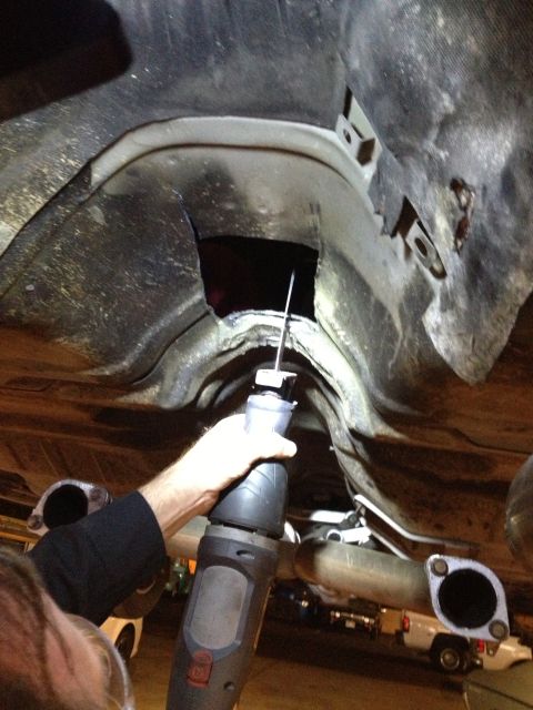2004 Ford Crown Victoria - A reciprocating saw cuts into the frame of a 2004 Ford Crown Victoria, likely for a transmission swap.