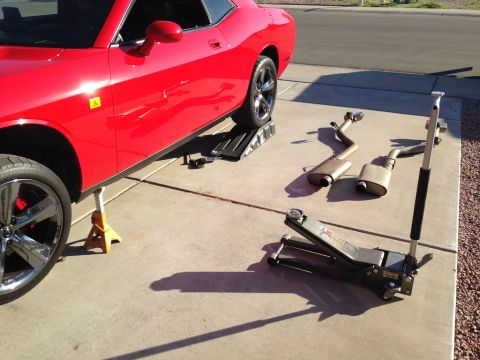 2010 Dodge Challenger - A red 2010 Dodge Challenger is shown on jack stands with its exhaust system removed, ready for maintenance.