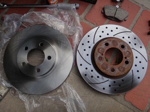 1993 Ford Taurus - New and old brake rotors are shown next to brake pads on a brick surface.