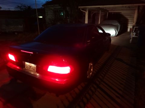 1993 Ford Taurus - Rear view of a 1993 Ford Taurus at night, showing illuminated brake lights and license plate.