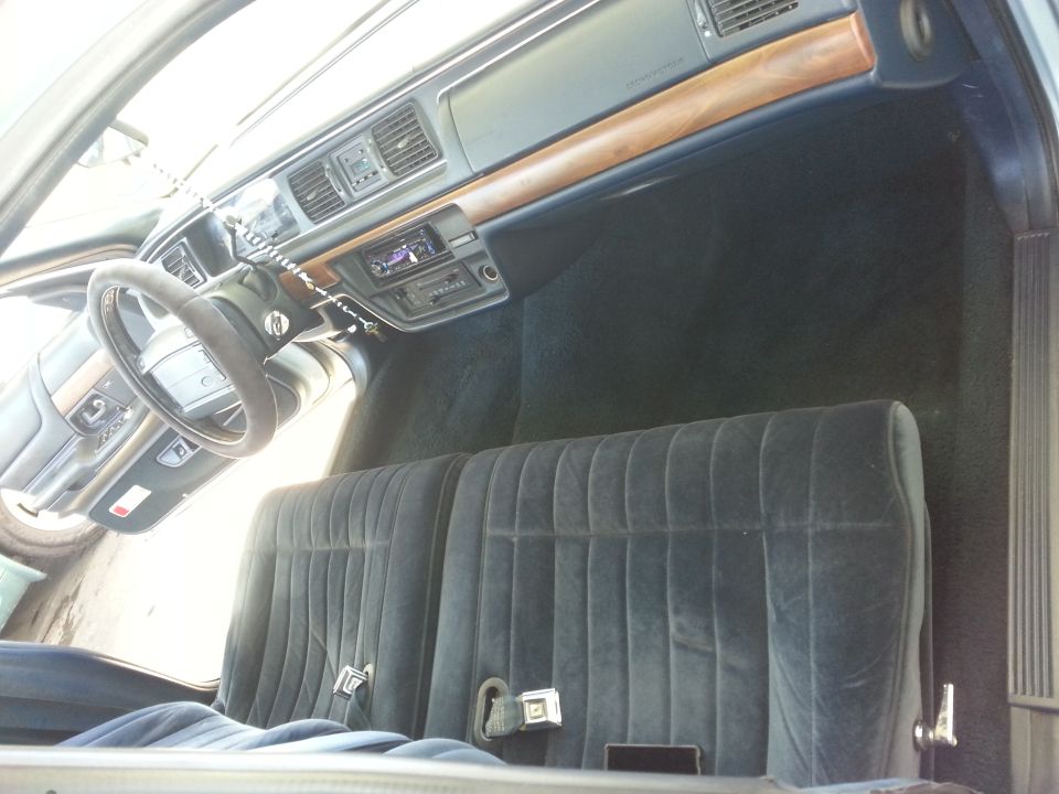 1992 Ford Crown Victoria interior with blue velour seats, wood trim dashboard, and aftermarket stereo