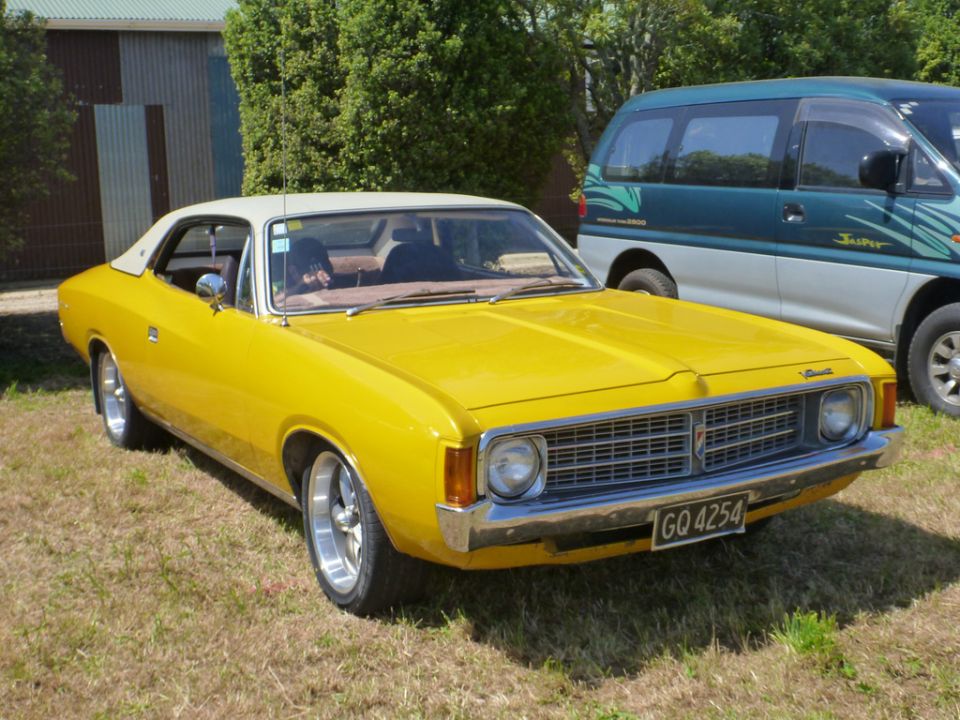 Yellow coupe with a white roof and chrome bumper, parked on grass. License plate GO 4254