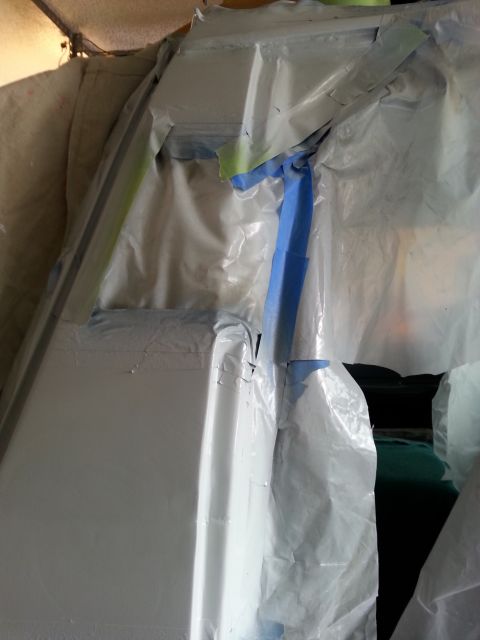 1992 Ford Bronco - A vehicle body panel is masked off and covered with plastic sheeting, ready for painting.
