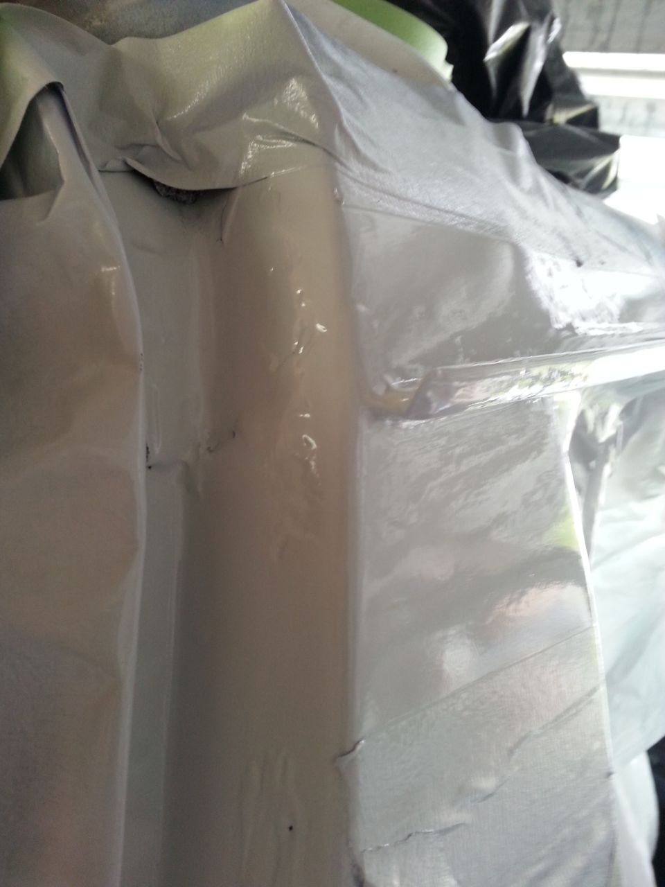 Vehicle body panel covered in plastic sheeting, with SuperMotors logo at bottom right