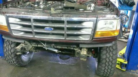 1996 Ford Bronco - This Ford truck is on a lift with its front end exposed, revealing the grille and engine components.