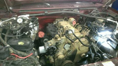1996 Ford Bronco - The engine bay of a vehicle shows a complex arrangement of hoses, wiring, and a large diesel engine.