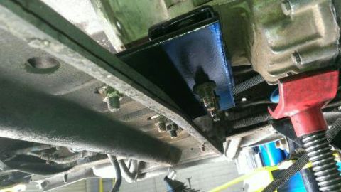 1996 Ford Bronco - Close-up view of an underbody component, possibly a transmission mount, being supported by a jack.