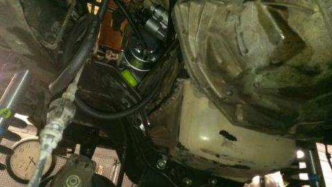 1996 Ford Bronco - A close-up view of the underside of a vehicle, showing various mechanical parts and hoses.
