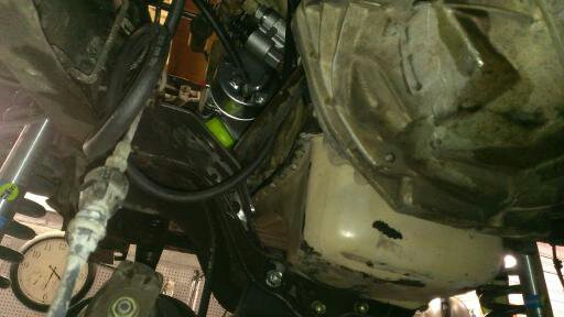Underside view of a vehicle's mechanical components, including hoses and parts of the engine or transmission