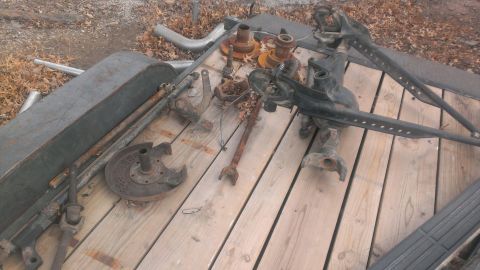 1986 Ford Bronco - A collection of old vehicle suspension parts are piled on a wooden trailer.