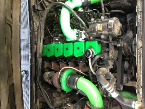 1995 Ford Bronco - Close-up view of a modified engine bay, showing custom green piping and turbocharger components.