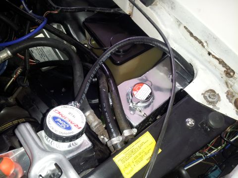 1976 Ford Ranchero - This image shows a close-up view of a vehicle's engine bay, focusing on the coolant reservoir and radiator cap.