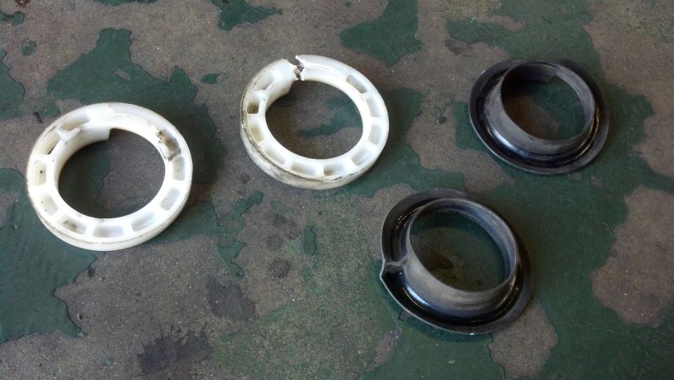 White plastic and black rubber suspension spring isolator rings on a shop floor