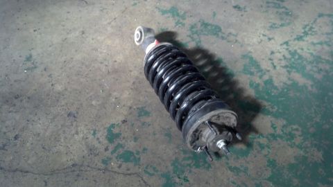2003 Ford Crown Victoria - black coil-over strut assembly with a wound coil spring rests on a stained concrete garage floor.