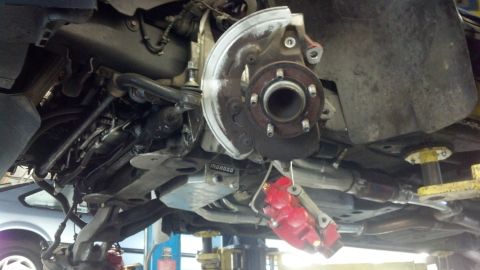 2003 Ford Crown Victoria - Underbody shot showing a wheel hub, brake rotor backing plate, control arms and a red brake caliper on a lift.