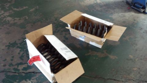 2003 Ford Crown Victoria - pair of new coil springs sit in open cardboard boxes on a green-stained concrete floor.
