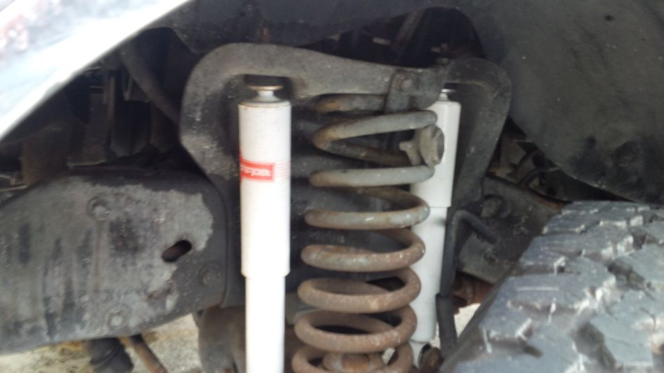 close-up of front suspension with coil spring and shock absorber, tire visible on right