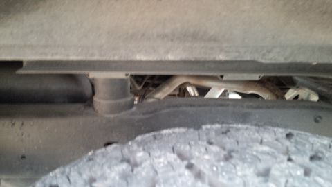 1992 Ford Bronco - A close-up view of the undercarriage of a vehicle, revealing the tire and exhaust system.