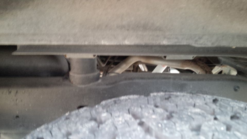 Underside view of a vehicle, showing the tire, frame, and exhaust pipe