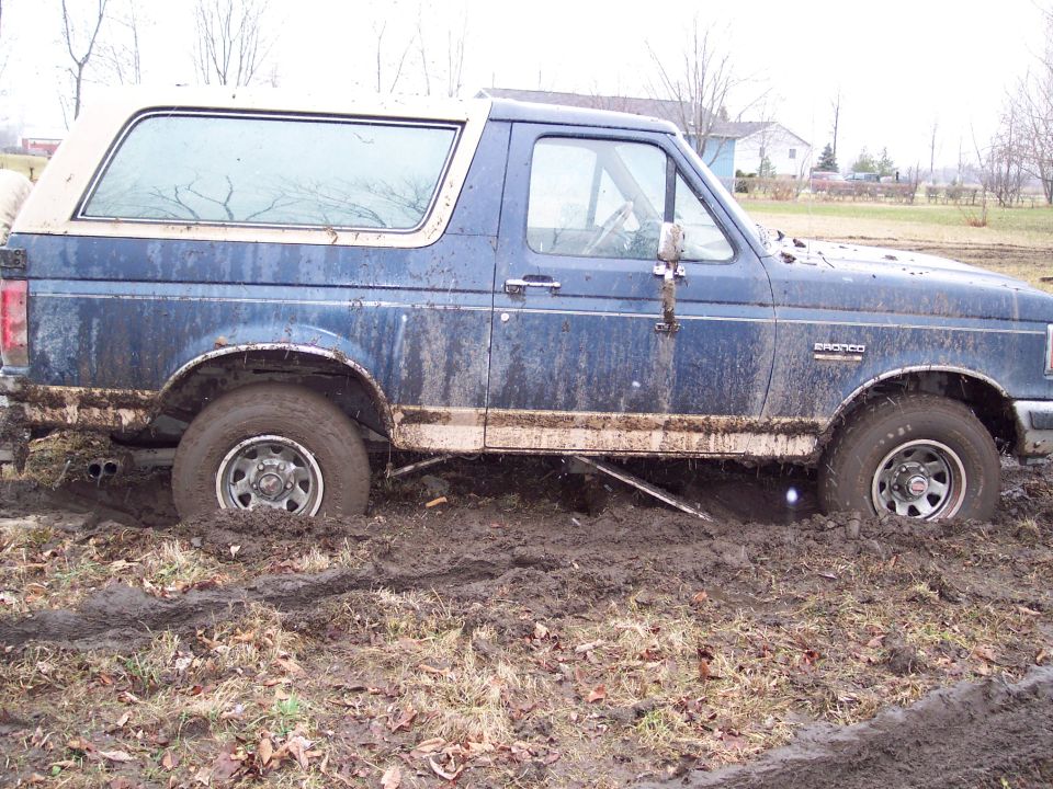 Blue 1987 Ford Bronco stuck in mud, side view