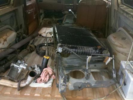 1982 Ford Bronco - Vehicle interior filled with disassembled engine parts, including a large radiator.