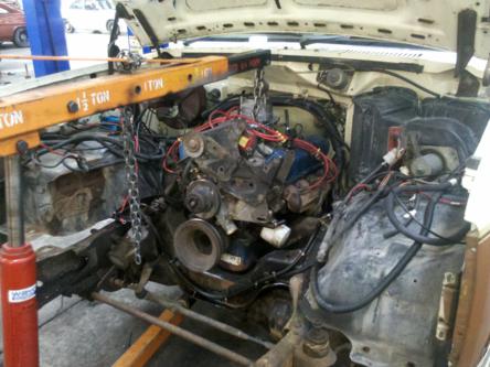 1982 Ford Bronco - Engine is being removed from the vehicle with an engine hoist. The engine bay is exposed.