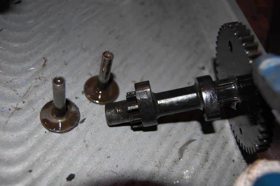 Engine camshaft and valves with oil residue on a gray surface