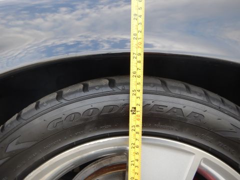 2003 Ford Crown Victoria - Close-up of a Goodyear-branded tire and silver alloy wheel with a tape measure held against an open sky.