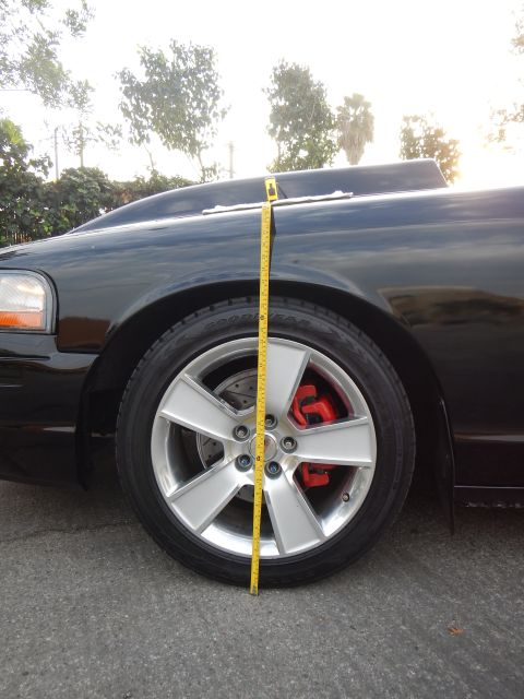 2003 Ford Crown Victoria - Portrait shot of a black sedan front wheel with a red brake caliper and a tape measure to the body line.