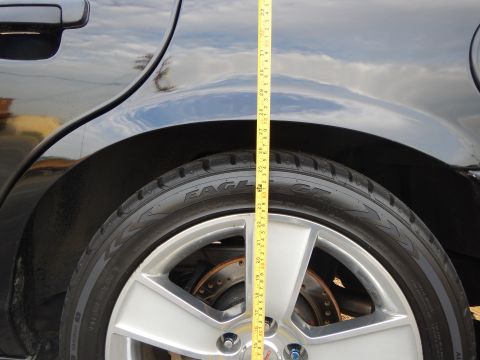 2003 Ford Crown Victoria - tape measure spans the rear wheel arch of a black car over a Goodyear Eagle tire and silver wheel.