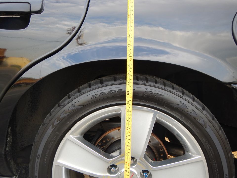 Rear wheel arch of a black car with a Goodyear Eagle tire and a tape measure